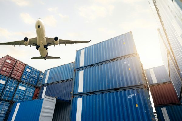 Air logistics. Cargo airplane flying above stack of logistic container. Cargo and shipping business.